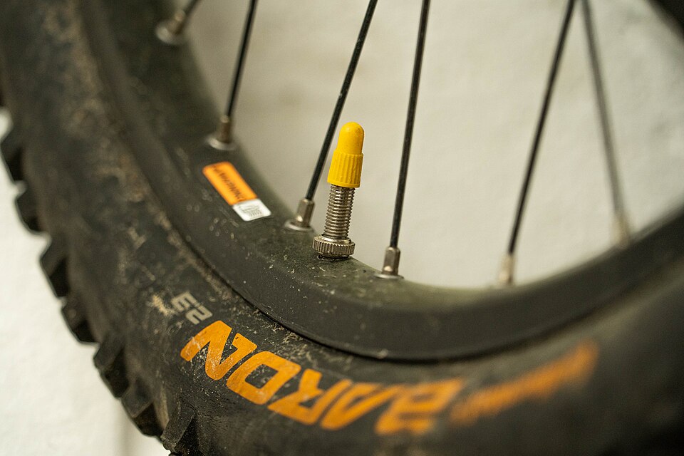 A Presta tire valve with a yellow cap on a mountain bike rim